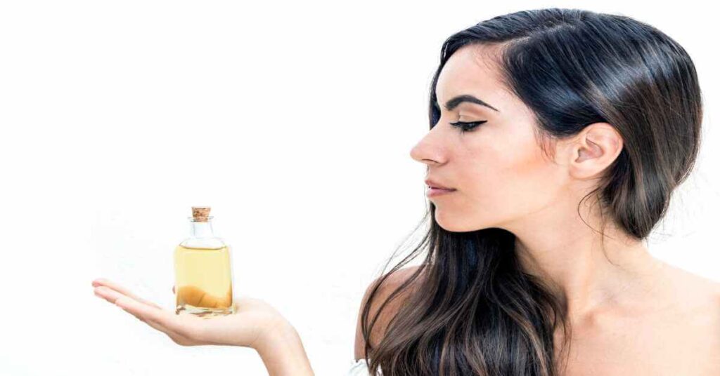 a girl holding batana oil in hand